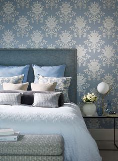 a bed with blue and white wallpaper in a bedroom next to a night stand