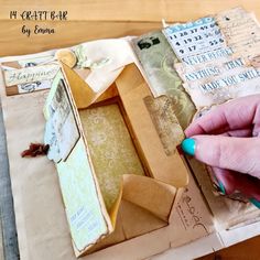 a person is making a small box out of old papers and other paper machs