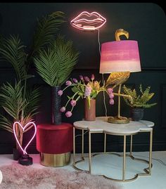 three different types of plants in vases on a table with a pink lamp next to them