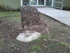 a metal chair sitting on top of a patch of dirt in front of a building