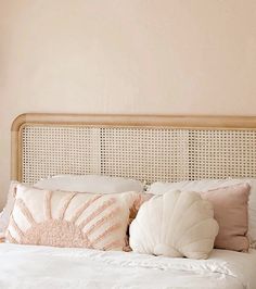 a white bed with pillows on top of it and a lamp above the headboard