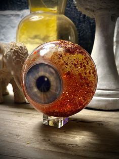 an eyeball sitting on top of a wooden table next to vases and statues