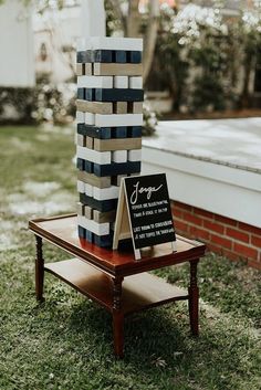 a wooden table topped with a black and white striped tower next to a brick building