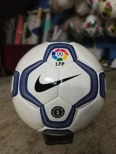 a white soccer ball with a blue and black stripe on the side sitting on a table