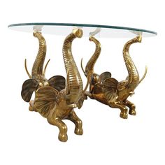 two brass elephants sitting under a glass table