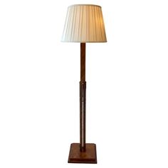 a lamp that is sitting on top of a wooden stand with a white lampshade