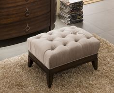 a small foot stool sitting on top of a shaggy rug in front of a dresser