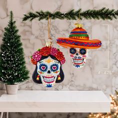 two ornaments are hanging on a shelf next to a christmas tree and potted plant