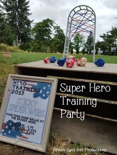 there is a sign that says super hero training party next to a bench in the grass