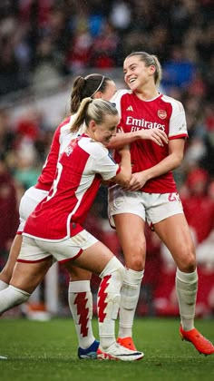 two female soccer players hugging each other on the field