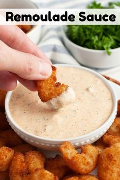 a hand dipping some tater tots into a small white bowl with ranch sauce