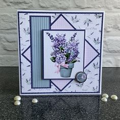 a card with purple flowers in a vase