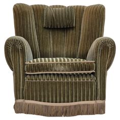 a green velvet chair with fringe trim around the armrests and back, on an isolated white background