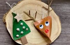 two christmas tree ornaments are on a wooden plate and one is made out of cardboard