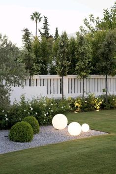 an outdoor garden with grass, bushes and lights