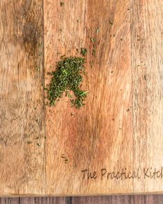 a wooden cutting board with herbs on it and the words the practical kitchen written in cursive writing