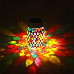 a colorful jar sitting on top of a table covered in colored lights and circles around it