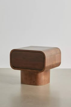 a wooden object sitting on top of a white table next to a gray wall and floor