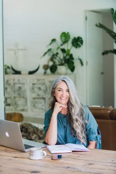 a woman sitting at a table with a laptop and coffee cup in front of her