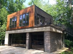 a two car garage with stone and wood on the outside, surrounded by green trees