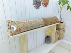 a wooden bench with a rug on it next to vases