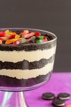 a trifle cake with cookies and candy in the middle on a purple tablecloth