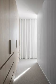 an empty hallway leading to a bedroom with white curtains