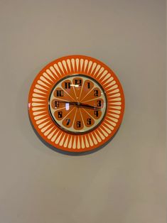 an orange and white clock hanging on the wall