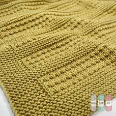 a knitted blanket that is yellow and has small squares on the top of it