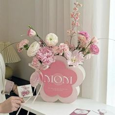 a woman standing next to a table with flowers and cards in front of her on it