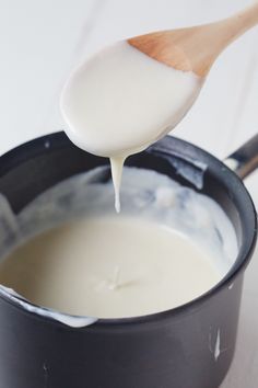 a spoon full of milk being poured into a pot