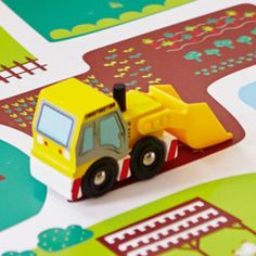 a yellow toy truck is parked on the road in front of a green and red map