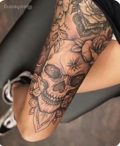 a woman's leg with flowers and skulls on it