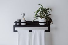 two white towels hanging on a towel rack next to a potted plant and candles