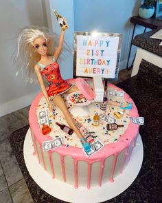 a barbie doll sitting on top of a birthday cake