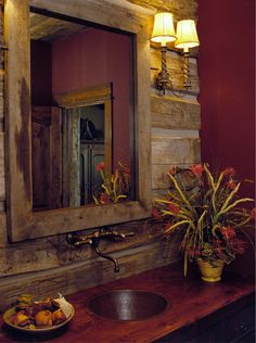 a bathroom sink sitting under a mirror next to a bowl of fruit on top of a wooden counter