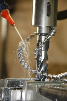 the machine is cutting metal parts with a small tool on it's head and has an orange handle