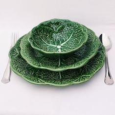 three green leafy plates with silverware on them and one has a fork next to it