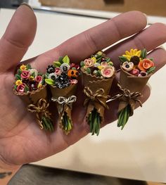 four miniature flowers are in the palm of someone's hand, which is holding them