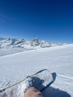 someone's feet in the snow with mountains in the background