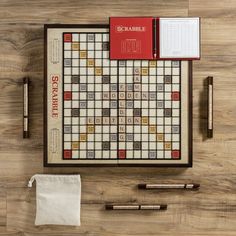 a scrabble board with pens, pencils and notepad on the table