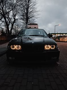 a black car is parked on the side of the road with its lights turned on