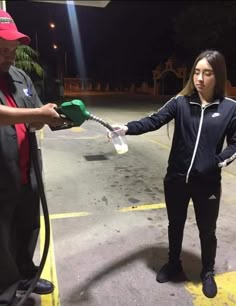 a woman is pumping gas into her car at night