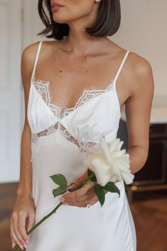 a woman in a white dress holding a flower