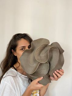 a woman is holding up a sculpture in front of her face