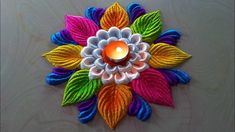 a candle is lit in the center of a colorful flower design on a white surface