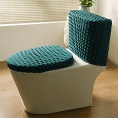 a white toilet sitting on top of a wooden floor next to a potted plant