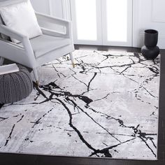 a white chair sitting on top of a wooden floor next to a black and white rug