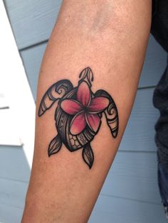 a tattoo on the arm of a woman with a pink flower and sea turtle design