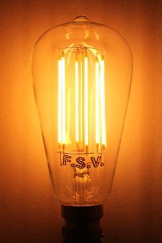 an old fashioned light bulb is lit up on the wall in front of a dark background